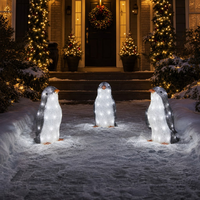 Light-up penguins lining a snowy front walkway at night